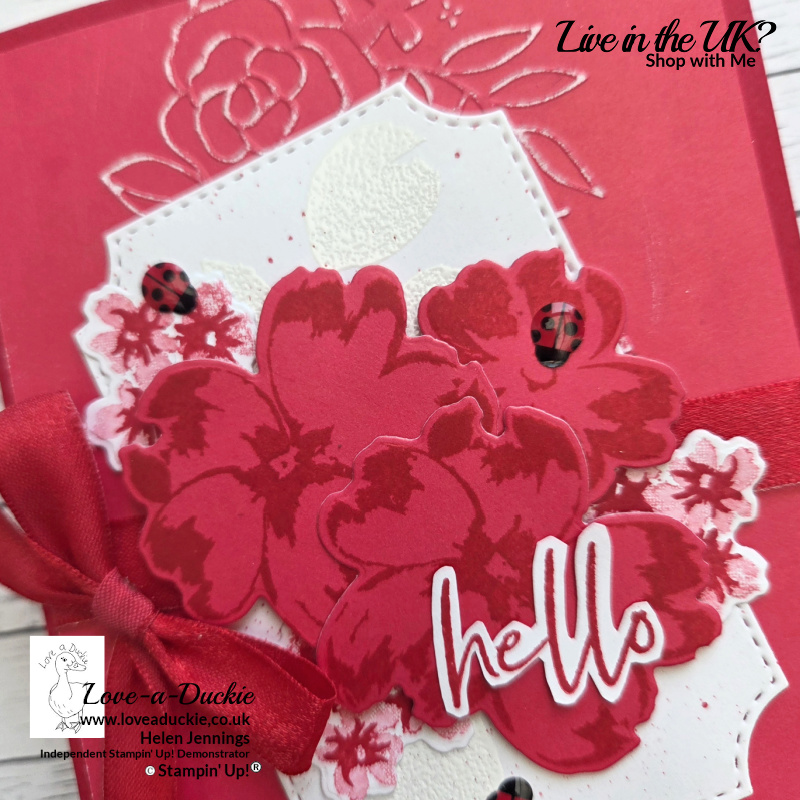 Close-up of layered red floral embellishments on a monochromatic card showing texture, dimension and white embossed background detail.