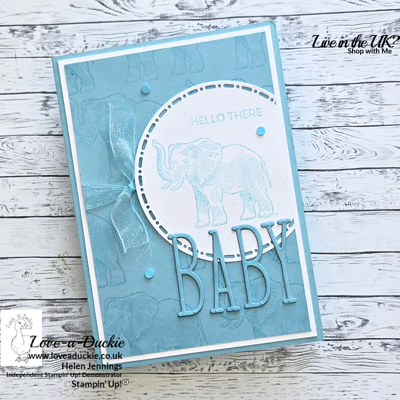 Balmy Blue monochromatic handmade baby card featuring tone-on-tone stamped elephant background, layered BABY die cut sentiment, ribbon detail and circular focal panel.